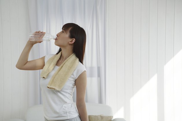 Young Woman Drinking Bottle of Water, Side View