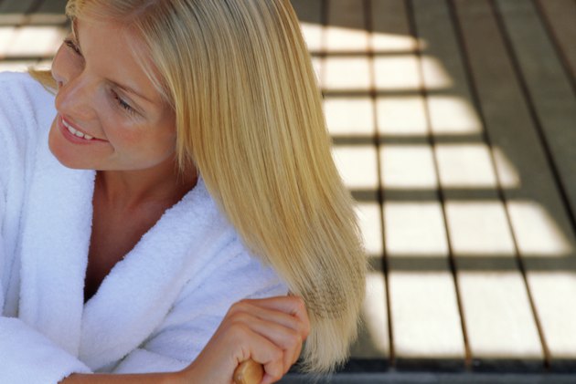 Woman in bathrobe brushing hair outdoors