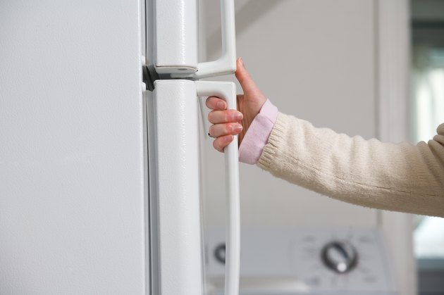 Hand of woman opening refrigerator door