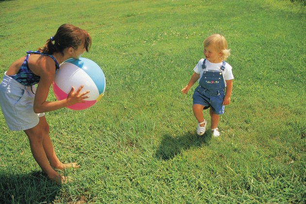 Girl and baby sister playing with beach ball