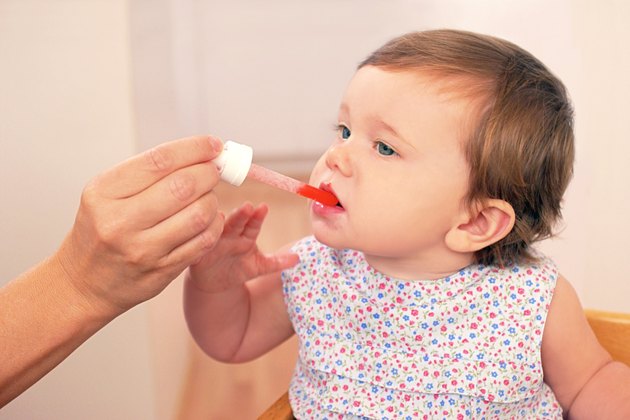 A mother gives her baby girl medicine with a medicine dropper.