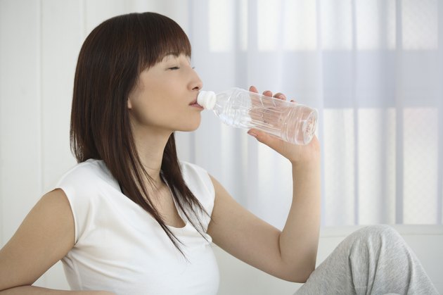 Young Woman Drinking Bottle of Water, Side View