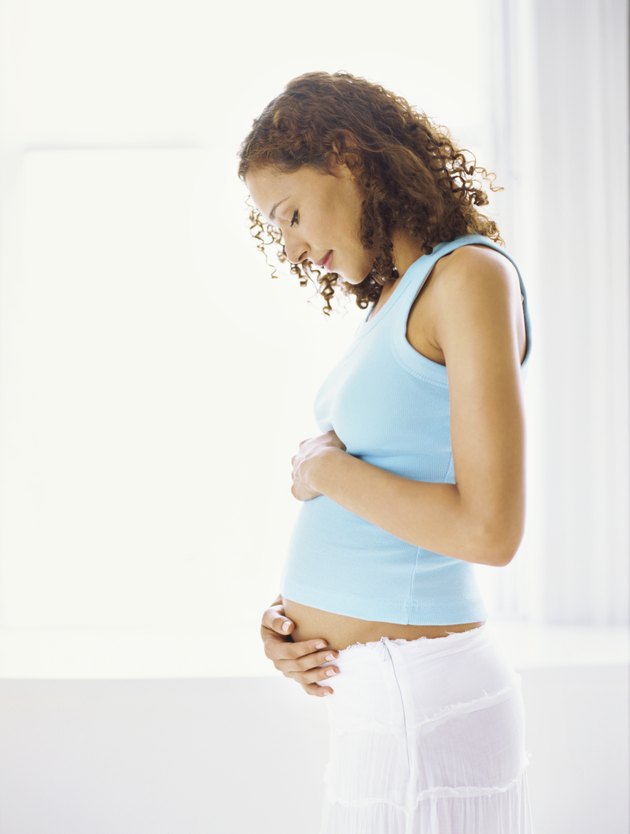 side profile of a pregnant woman touching her abdomen