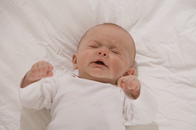 Unhappy baby lying down with eyes closed