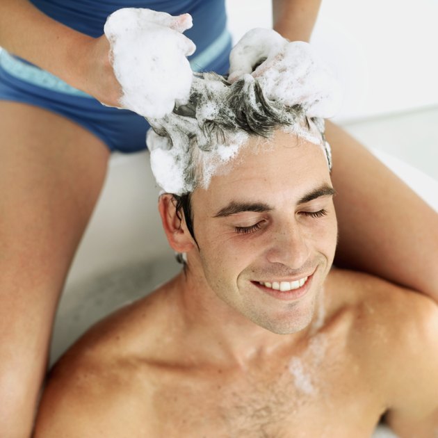 close-up of a young man getting his hair washed by a woman