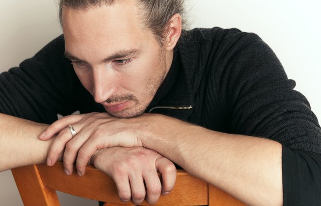 Sad young Asian man sitting on wooden chair