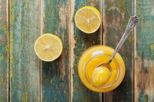Lemon curd in jar on rustic wooden table, top view