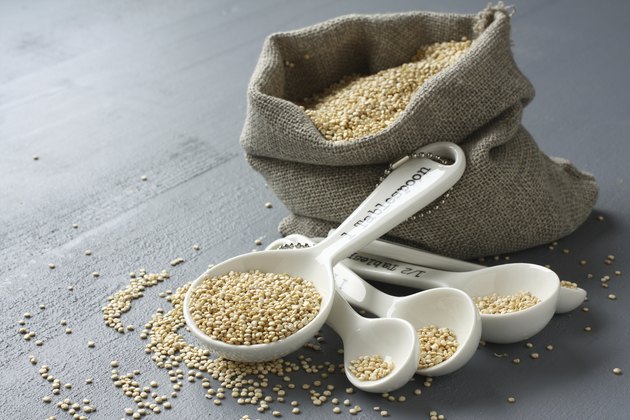 Quinoa grain in small burlap sack and porcelain measuring spoons