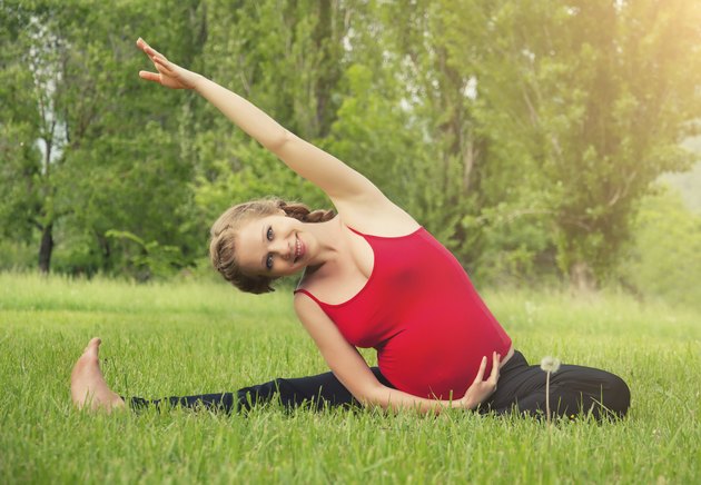 healthy pregnant woman doing yoga in nature