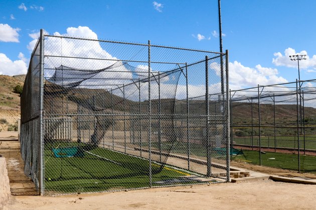 Batting cages with blue sky, puffy clouds and rolling hills