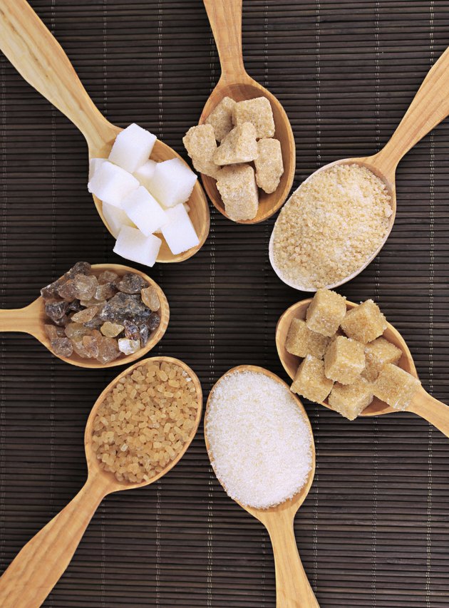 Different types of sugar in spoons on table close-up