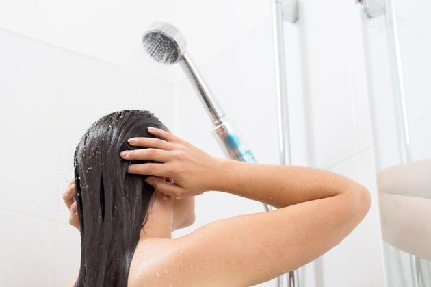 Shot of a young woman washing her hair in a shower
