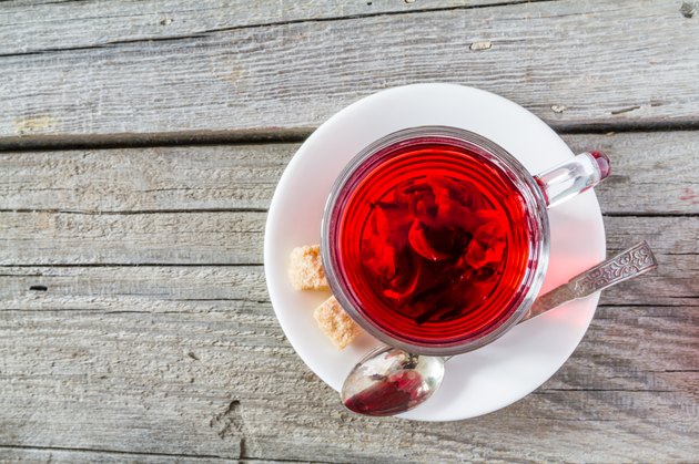 Hibiscus tea in glass cup, rustic wood background