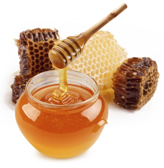 Pot of honey and wooden stick.