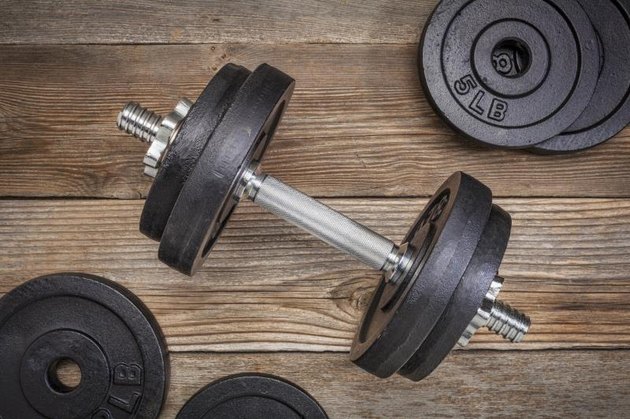 exercise weights - iron dumbbell with extra plates on a rustic wooden deck
