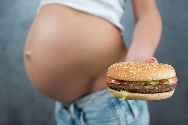 Close up of a cute pregnant belly and junk food