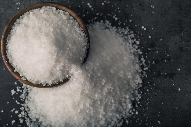 Salt. Coarse grained sea salt on granite - concrete stone background with vintage spoon and woden bowl.Salt. Coarse grained sea salt on granite - concrete stone background with vintage spoon and wooden bowl.