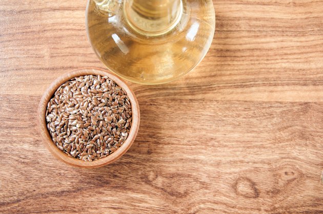 Flax seeds in wooden bowl , linseed oil on wooden background