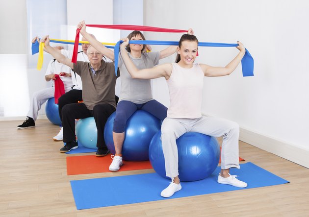 People With Resistance Bands Sitting On Fitness Balls
