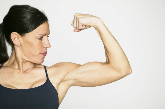 Young woman flexing muscles in studio, portrait