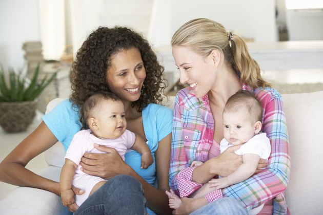 Two Young Mothers With Babies On Sofa At Home
