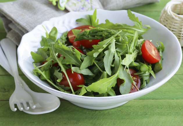 salad with arugula and tomatoes served on a wooden table