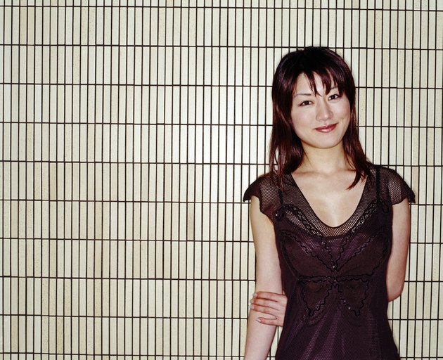Young woman standing in front of tile wall, smiling, portrait