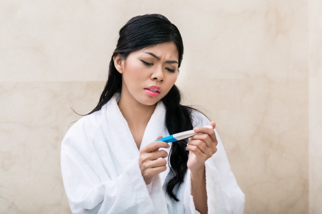 Asian woman being sad with pregnancy test