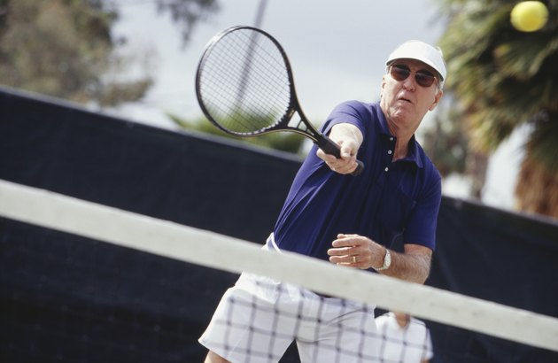 Man wearing sunglasses playing tennis outdoors