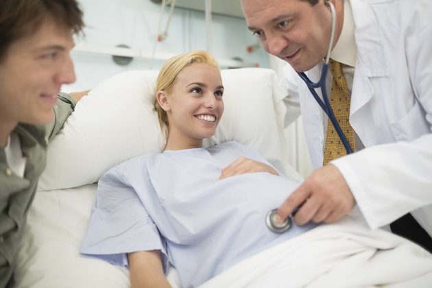 Smiling doctor using a stethoscope on pregnant woman