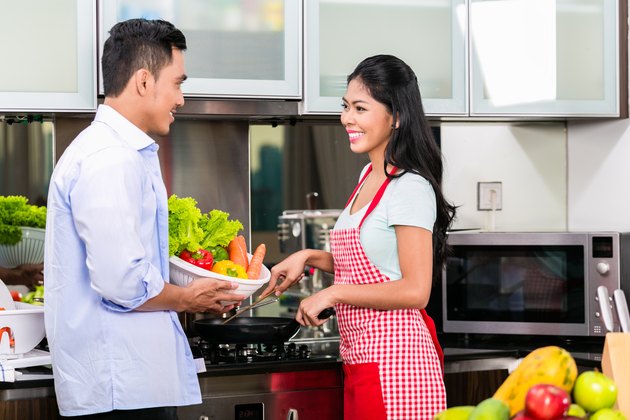 一起烹调食物的亚洲夫妇在厨房里