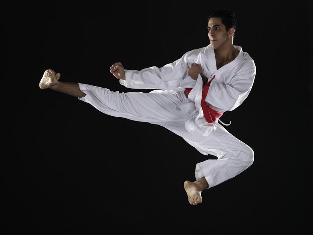 Young man practicing martial arts, jumping in midair