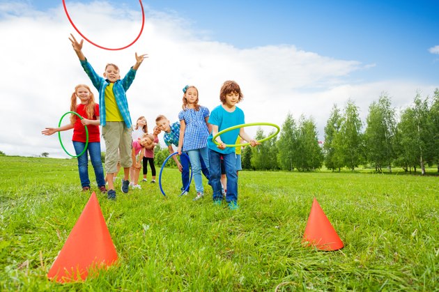 Happy children throw colorful hoops on cones