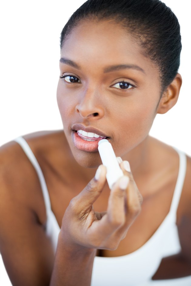 Pretty woman putting lip balm on her lips
