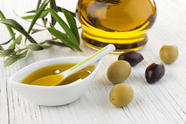 Olive oil and green and black olives on white