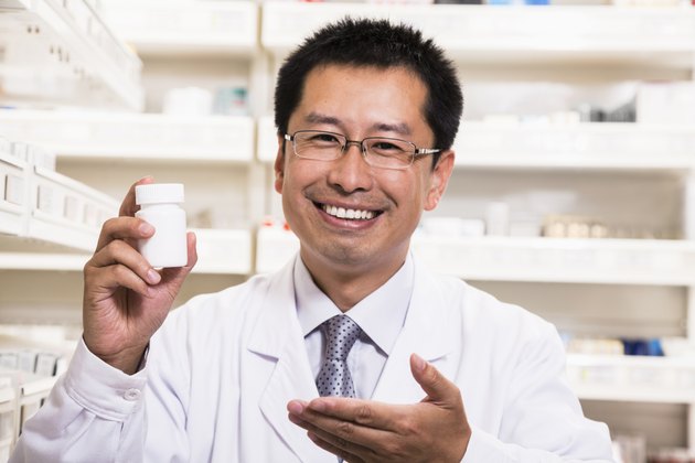 Portrait of smiling pharmacist holding a prescription medication bottle in his hand