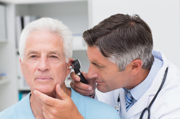 Doctor examining senior patients ear with otoscope