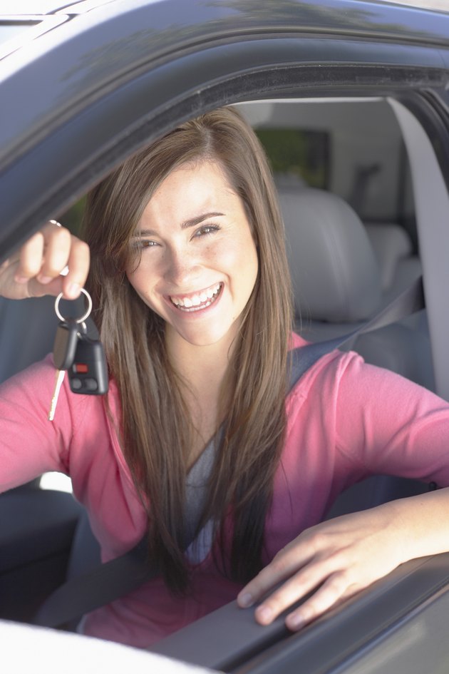 Smiling teenage girl holding keys inside car