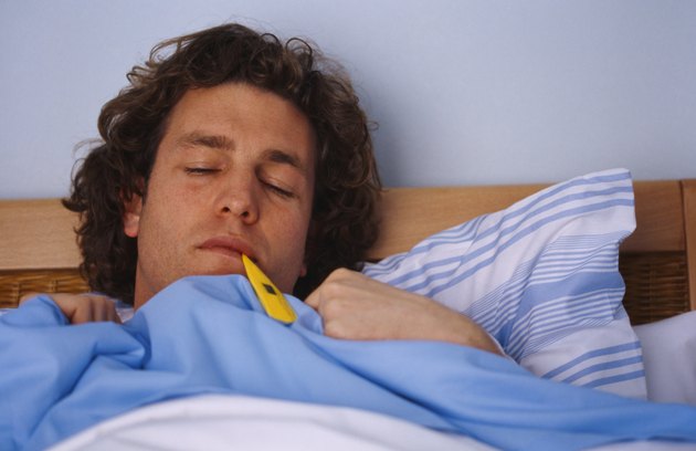 Close-up of a man in bed with a thermometer in his mouth