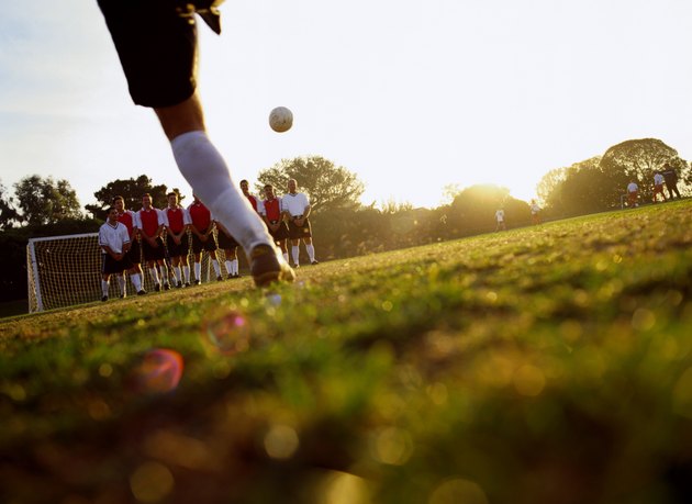 Soccer player kicking ball towards goal, ground view