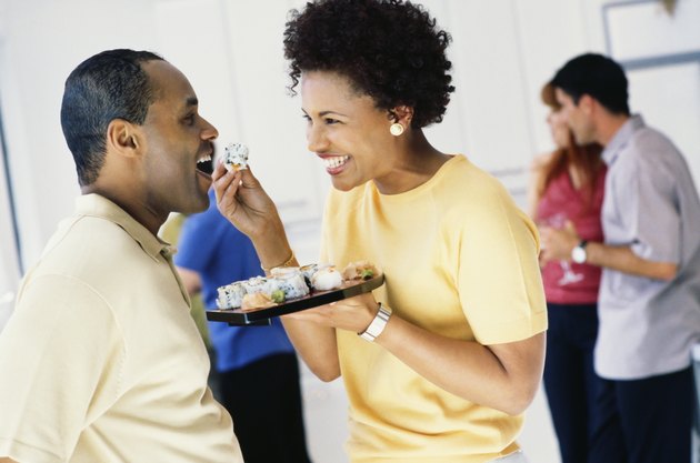 African woman feeding husband sushi