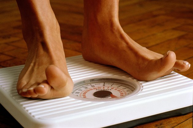 Woman weighing herself on bathroom scales,detail of feet