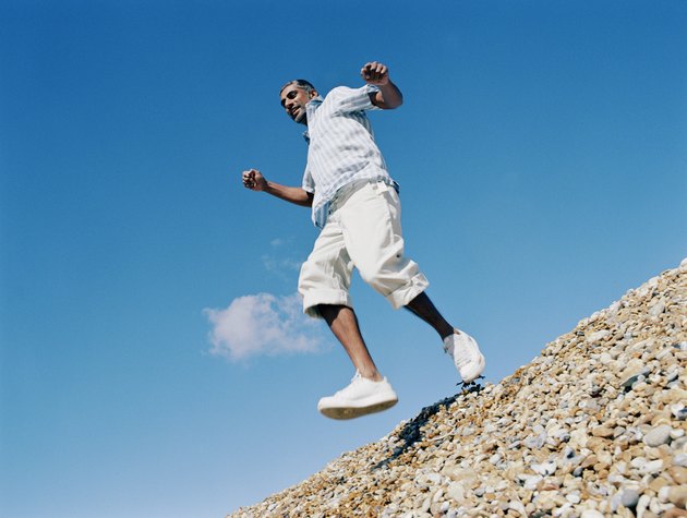 Man skipping on pebble beach, low angle view