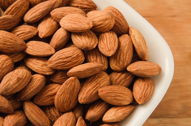 Healthy snack almond kernels in white bowl