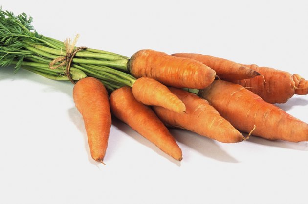 Bunch of carrots on counter with stems and leaves at top of image, close-up