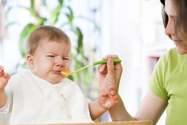 Unhappy baby boy refusing to eat food.