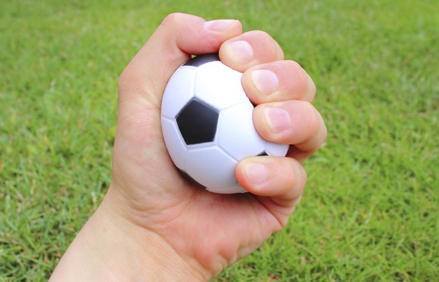 Small stress ball in hand of man on grass background