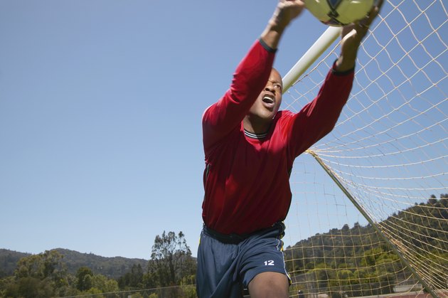 Young man holding a football near a goal post