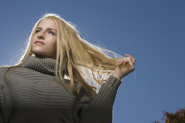 Portrait of carefree blonde woman outdoors running hand through hair