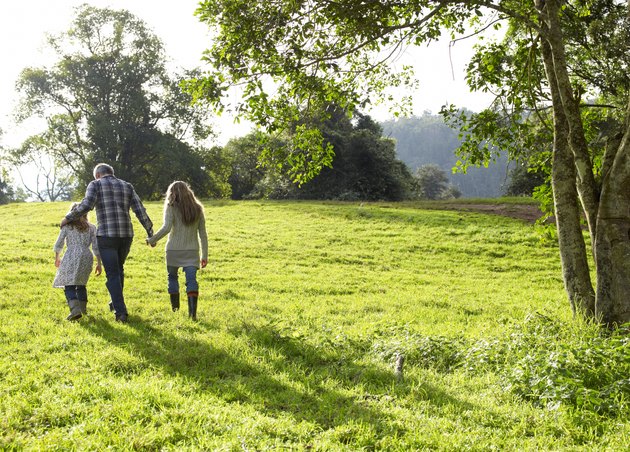 Family walking up a grassy hill together